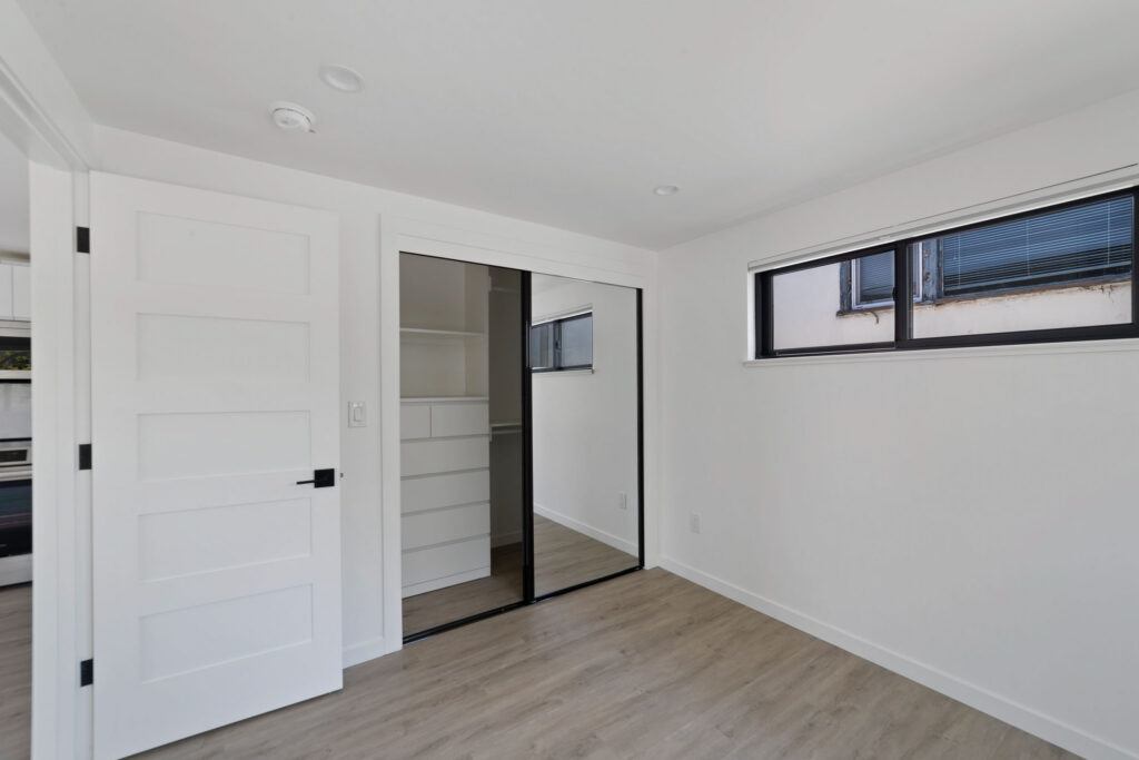 Bedroom with mirrored closet doors, built-in shelving, and a high horizontal window.